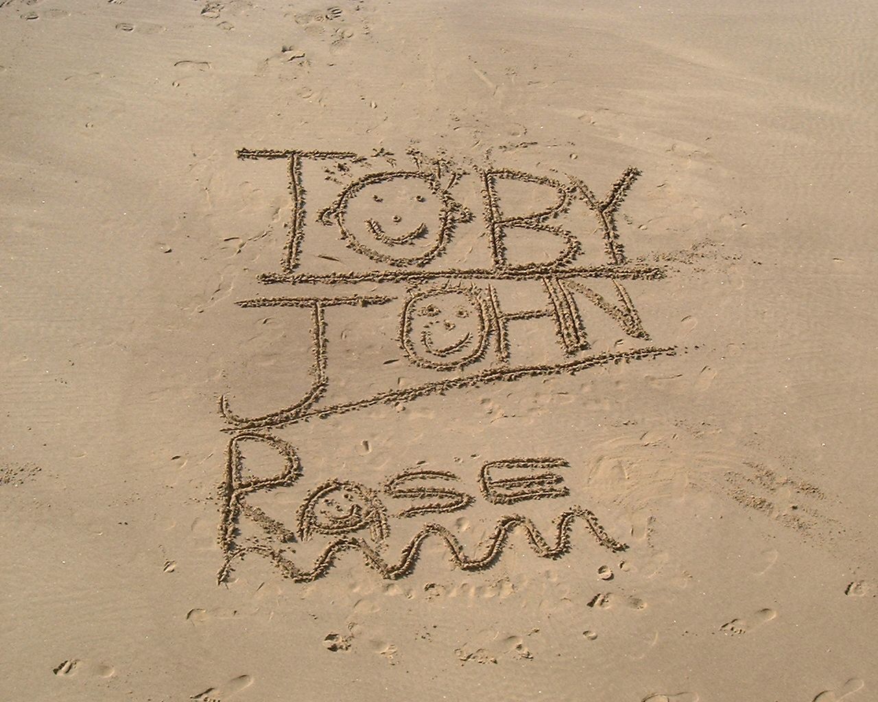 Toby, John and Rose's names written in the sand. On the beach in Whitby, taken from above. It's a glorious sunny day.